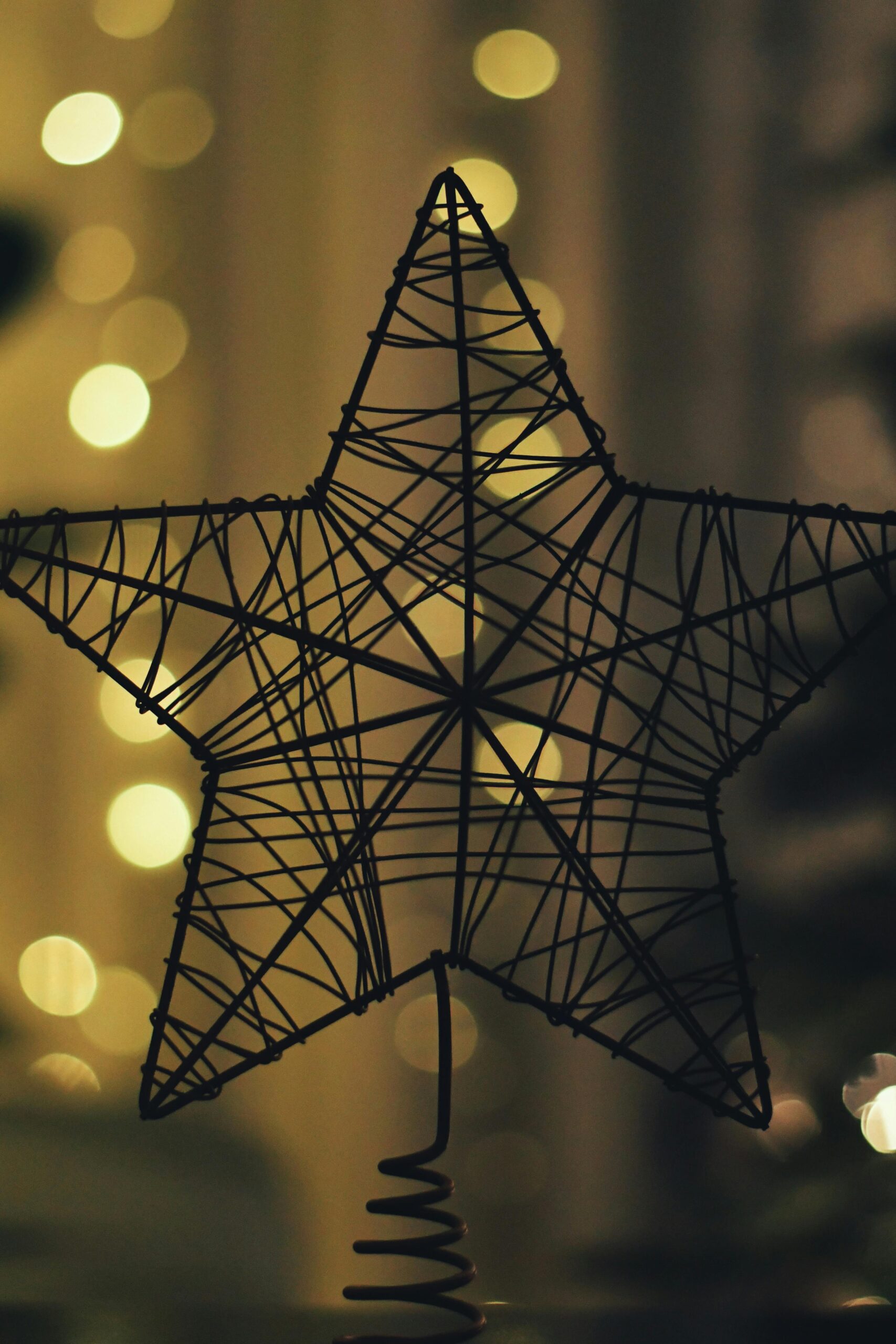 Stylish wire star decoration backlit with warm, blurry bokeh lights for a festive ambiance.